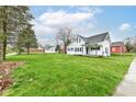 View of the home with a large grassy yard, mature trees, and a detached garage at 121 Illinois St, Shirley, IN 47384