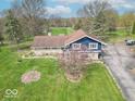 An elevated view showcasing a blue and stone home with a well-kept lawn and an expansive driveway at 12166 N Bray Rd, Mooresville, IN 46158