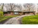 Charming single-story brick home featuring a well-maintained lawn and mature trees, offering curb appeal at 123 W 81St St, Indianapolis, IN 46260