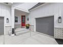 Inviting front porch featuring a red door, gray two-car garage, and stylish exterior lighting at 16422 Brigham Ln, Westfield, IN 46074