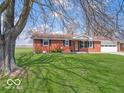 Quaint single-story brick home with lush green lawn and mature trees, offering a serene and inviting curb appeal at 1734 Bittersweet Dr, Anderson, IN 46011