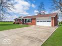 A cozy single-story brick home with a sprawling green lawn, complemented by an attached garage and long drive at 1734 Bittersweet Dr, Anderson, IN 46011