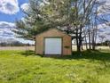 A shed with brown wooden exterior and a white garage door is surrounded by lush green grass and trees at 2715 S 300 E, Anderson, IN 46017