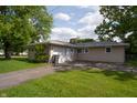 View of the home's back exterior and detached garage with a spacious driveway and grassy area at 3140 Bonham Dr, Indianapolis, IN 46222