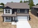 Two-story home featuring a gray roof, white garage door, and dark siding, sitting on a construction lot at 3315 Godby Dr, Sheridan, IN 46069