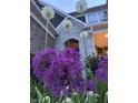 Lush front yard featuring vibrant purple Allium flowers and a stone and brick home in the background at 3665 Conifer Dr, Zionsville, IN 46077