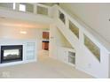 Cozy living room with fireplace, built-in shelving, staircase with glass, and a view into the kitchen at 4959 Clarkson Dr, Indianapolis, IN 46254