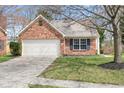 Brick home featuring an attached garage, well-kept lawn, and complemented by a mature tree at 5105 Hawks Crescent Ct, Indianapolis, IN 46254