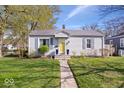Charming single-story home featuring a well-maintained lawn, inviting yellow front door and blue shutters at 5277 Kingsley Dr, Indianapolis, IN 46220