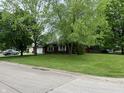 A well-manicured lawn enhances this home's curb appeal, complemented by mature trees providing shade at 605 Queenswood Dr, Indianapolis, IN 46217