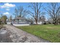 View of a charming single-story home with gray siding and a paved driveway with a detached garage at 6303 Bertha St, Indianapolis, IN 46241