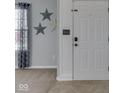 View of the foyer with neutral walls and a white front door with decorative molding, creating a welcoming atmosphere at 6613 Harvest Ridge Ct, Indianapolis, IN 46237