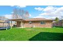 View of a spacious backyard with green grass, a covered patio, and blue trampoline at 715 Pioneer Dr, Indianapolis, IN 46217