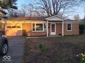 Brick home with mature trees, featuring a pink garage door and tidy front lawn at 721 1St Ne Ave, Carmel, IN 46032