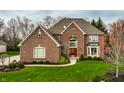 Charming brick home with a red front door, lush green lawn, and beautifully landscaped front yard at 7326 Elm Ridge Dr, Indianapolis, IN 46236