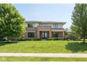 Two story brick home with a large front lawn, manicured shrubs and mature trees creating a welcoming and picturesque setting at 13225 Gatman Ct, Carmel, IN 46032