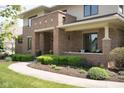 Charming covered front porch with brick columns, cozy seating, and beautifully landscaped surroundings for a relaxing outdoor space at 13225 Gatman Ct, Carmel, IN 46032