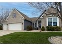 Charming brick home featuring a two-car garage, manicured lawn, and classic architectural details under a beautiful sky at 2890 Trillium Way, Columbus, IN 47201
