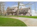 Stately home with stone and Tudor accents, surrounded by lush greenery and mature trees at 3892 Arrowhead Ct, Greenfield, IN 46140