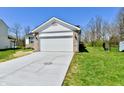 A two-car garage with concrete driveway and adjacent green lawn under a bright blue sky at 4064 Waterfield Dr, Indianapolis, IN 46235