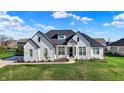 Beautiful home with black roof accents, crisp white siding, a manicured lawn, and beautiful landscaping at 5492 Cottage Grove Ln, Noblesville, IN 46062