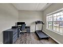 A home office featuring a desk setup, a dark color scheme, wood floors, and a treadmill near a bright window at 6674 Buhrstone Ln, Avon, IN 46123