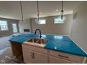 New kitchen island with a dual sink and modern lighting fixtures, all covered in protective plastic at 7421 Broadview Ln, McCordsville, IN 46055
