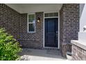 Inviting front porch with brick accents, a dark front door, and a charming outdoor light fixture at 10602 Pintail Ln, Indianapolis, IN 46239