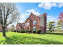 View of a two-story brick and vinyl home with a well-maintained lawn and blooming tree at 11599 Braemar Ct, Carmel, IN 46032