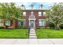 Inviting townhouse featuring a red brick facade, dormer windows, and well-maintained lawn at 13510 E 131St St, Fishers, IN 46037