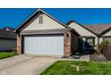 Charming home featuring a two-car garage, brick accents, complemented by lush green lawn and blue skies at 1720 Justin Ct, Indianapolis, IN 46219