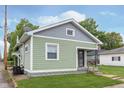 Exterior view of charming home featuring green siding, grey shingle, covered porch and well-maintained lawn at 217 W 35Th St, Indianapolis, IN 46208