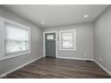 Bright living room with wood floors, neutral walls, large windows, and a modern front door at 217 W 35Th St, Indianapolis, IN 46208