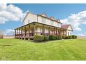 Wide view of home with covered porch, lush lawn, and distant field, showcasing a country-style charm at 4339 W Briarwood Rd, Monrovia, IN 46157