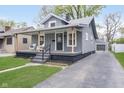 Inviting gray house featuring a cozy front porch, fresh lawn, and a private driveway at 4719 Evanston Ave, Indianapolis, IN 46205