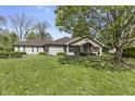 Tan home featuring a covered porch with bushes out front and an overgrown lawn at 8560 N College Ave, Indianapolis, IN 46240