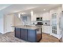 Bright kitchen boasts white cabinets, stainless appliances, a kitchen island, and leads to the stairs at 9844 Plantana Blvd, Fishers, IN 46038