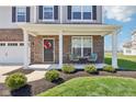 Inviting front porch with decorative wreath and seating, complementing the home's brick facade at 9916 Gallop Ln, Fishers, IN 46040