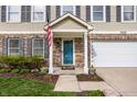Inviting front porch with blue door, manicured landscaping, and brick accents creates a welcoming entryway at 10220 Tournon Dr, Fishers, IN 46037