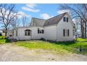 Side view of a two-story white home with dormers, windows, and gravel driveway at 11015 S State Road 58, Columbus, IN 47201