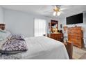 Light filled bedroom with hardwood floors, ceiling fan, dresser, and large bed at 11015 S State Road 58, Columbus, IN 47201