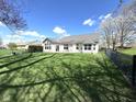 Spacious backyard with lush green grass and mature trees, enclosed with a black metal fence at 11602 Fairgreen Dr, Carmel, IN 46032