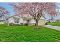 Attractive single-story home featuring green lawn, flowering tree and two car garage in a suburban setting at 118 Presidential Ct, Greenfield, IN 46140