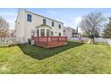Expansive backyard featuring a wooden deck, lush green lawn, and a white picket fence, ideal for outdoor entertaining at 14538 Baldwin Ln, Carmel, IN 46032