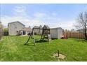 Spacious backyard with green grass, a playground set, storage shed, and wood privacy fence at 14953 Lovely Dove Ln, Noblesville, IN 46060