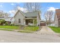 Two-story home with a detached garage and long driveway on a sunny day at 304 W 4Th St, Greenfield, IN 46140