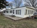 A manufactured home featuring white siding, gray shutters, and a small concrete patio with outdoor seating at 4653 E Us Highway 36, Markleville, IN 46056