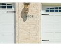 Close-up of house number detail on brick exterior near white garage doors and carriage lighting at 4858 Brentridge Pl, Greenwood, IN 46143