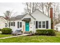 Charming home featuring a bright teal front door, landscaped yard, and cozy seating area on the front porch at 5140 Indianola Ave, Indianapolis, IN 46205