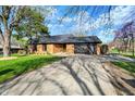 Brick home with an attached garage, driveway, and green lawn with a mature tree on the side at 601 Ridge Rd, Greenwood, IN 46142